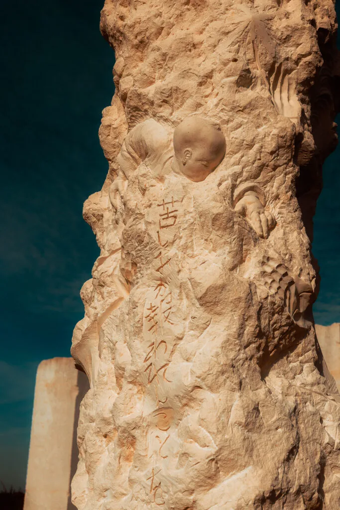 Sculpture représentant un enfant semblant émerger de la pierre à la Galaxie des Pierres Levées
